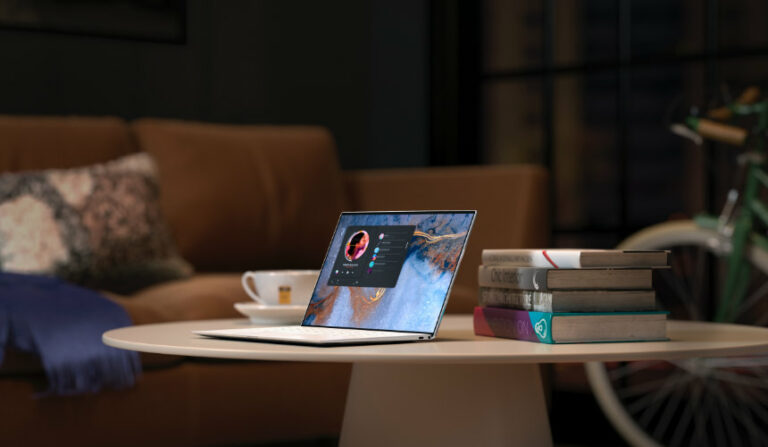 laptop on a table with a pile of books next to it in a darkly lit coffee shop